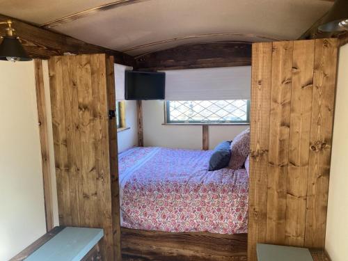 a small bedroom with a bed and a window at Modern Shepherd's Hut at St Anne's in Plymouth