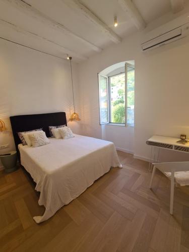 a white bedroom with a large bed and a table at Apartment Tomazina (seaview,central, heritage) in Vis