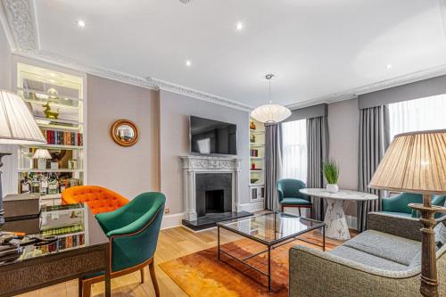 a living room with a fireplace and green chairs at Flemings Mayfair - Small Luxury Hotel of the World in London