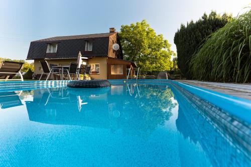 a swimming pool with blue water in front of a house at Penzion Mona in Jeseník