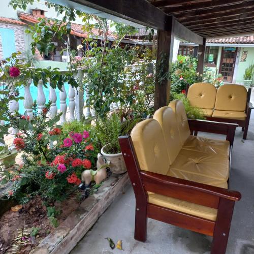 a porch with two chairs and flowers and a fence at Pousada Lagomar da Barra de Marica in Maricá