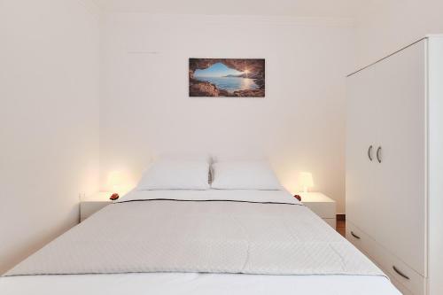 una camera bianca con un letto e una foto appesa al muro di Casa Mazzini a Matino