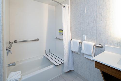 a bathroom with a white tub and a sink at Holiday Inn Express Fresno South, an IHG Hotel in Fresno