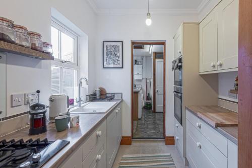 a kitchen with white cabinets and a counter top at Beautiful Redbrick Home in Ruthin Centre & Parking in Ruthin
