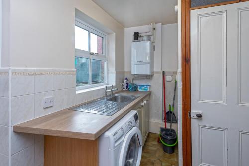 a kitchen with a sink and a washing machine at Beautiful Redbrick Home in Ruthin Centre & Parking in Ruthin