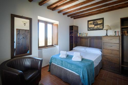 um quarto com uma cama e uma cadeira em Convento dei Cappuccini em Tolfa