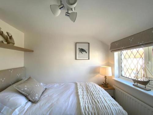 a bedroom with a white bed and a window at Cosy cottage 5 minutes walk to beach in Caister-on-Sea