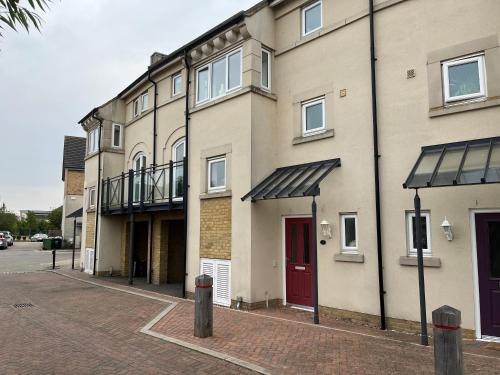 an apartment building with a red door on a street at Hampton Vale, Peterborough Lakeside Large Double bedroom with own bathroom in Peterborough
