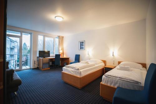 ein Hotelzimmer mit zwei Betten und einem Schreibtisch in der Unterkunft Hotel in Herrenhausen in Hannover