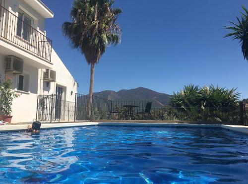 una piscina frente a una casa con palmeras en Garden Apartment, Cortijo Fruitful Hills, en Coín