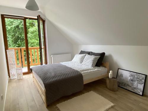 sypialnia z łóżkiem i dużym oknem w obiekcie Dom całoroczny nad jeziorem Brajnickim 