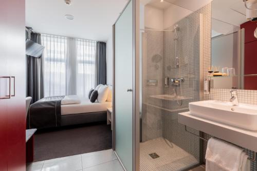 a bathroom with a shower and a sink and a bed at Select Hotel Berlin Gendarmenmarkt in Berlin