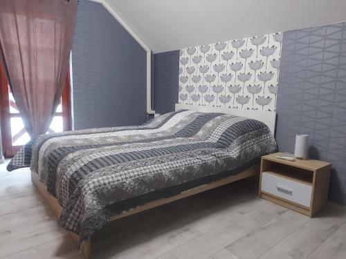 um quarto com uma cama com um edredão cinza e branco em Anikó Szállás Baja em Baja