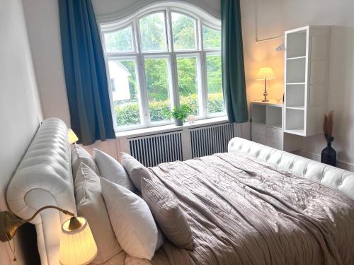 - une chambre avec un lit blanc avec des oreillers et une fenêtre dans l'établissement Villa Apartment near City Centre, à Bronshoj