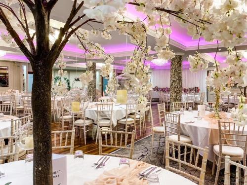 un salón de banquetes con mesas y sillas blancas y un árbol en The Terrace Hotel, en Magherafelt