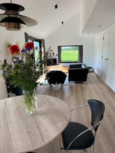a living room with a table with a vase of flowers at Bij De Kei Appelscha in Appelscha