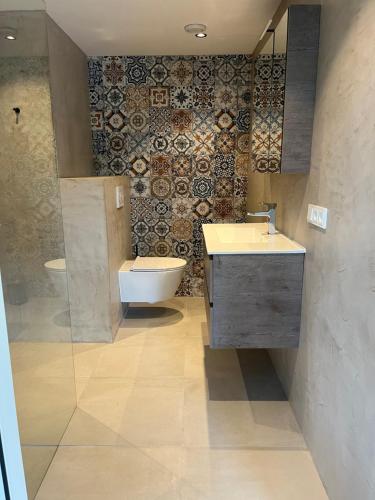 uma casa de banho com lavatório, WC e azulejos em Bij De Kei Appelscha em Appelscha