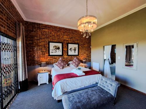 um quarto com uma cama grande e uma parede de tijolos em Dullstroom Manor Game & Trout Lodge em Dullstroom