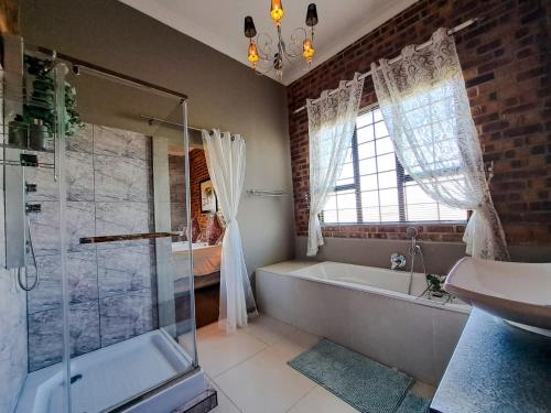 ein Badezimmer mit einer Dusche, einer Badewanne und einem Waschbecken in der Unterkunft Dullstroom Manor Game & Trout Lodge in Dullstroom