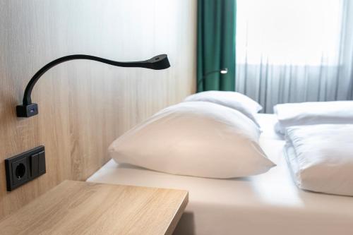 a black lamp sitting on a bed with pillows at ACHAT Hotel Monheim am Rhein in Monheim