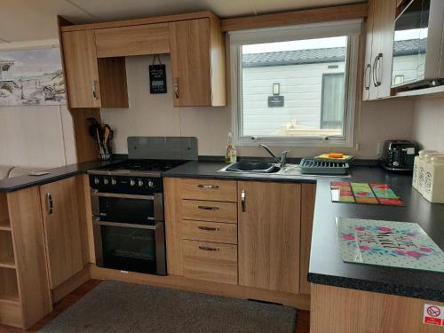 a kitchen with a stove and a sink and a window at 95 Holiday Resort Unity 3 bed passes included in Brean