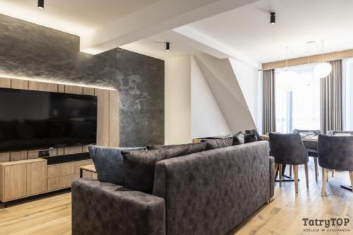 a living room with a couch and a table with chairs at TatryTop Apartamenty Sabała in Zakopane