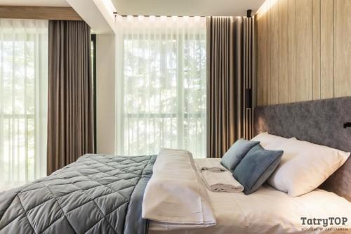 a bedroom with a bed and a large window at TatryTop Apartamenty Sabała in Zakopane