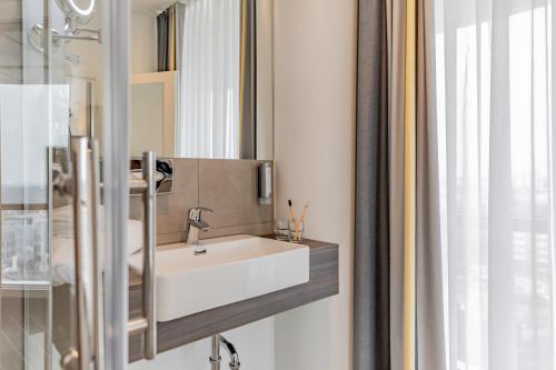 uma casa de banho com um lavatório branco e um espelho. em Select Hotel Berlin Spiegelturm em Berlim