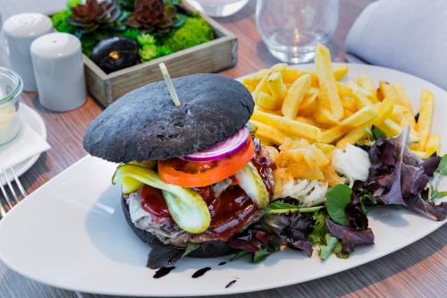 a white plate with a sandwich and french fries at Garner Hotel Berlin - Spandau by IHG in Berlin
