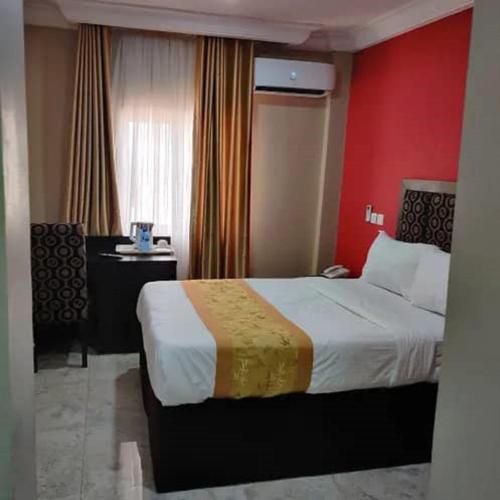a hotel room with a bed and a red wall at Belmont Hotel in Wupa