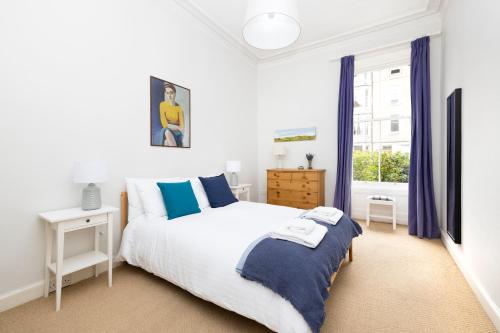 a white bedroom with a bed and a window at JOIVY 3-bed Meadows flat near Castle in Edinburgh