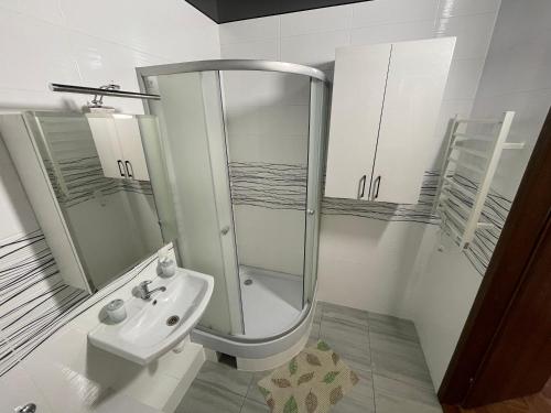 a white bathroom with a shower and a sink at Квартира в новому будинку in Kyiv