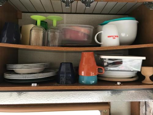 a kitchen shelf with dishes and utensils at BED & BREAKFAST 5 MIN FROM e47 - DOGS WELCOME - COSY FARM BnB in Tureby