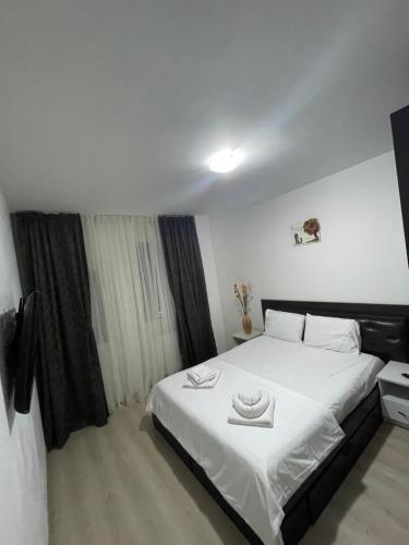 a bedroom with a large white bed with two hats on it at Apartament ELLA in Tulcea