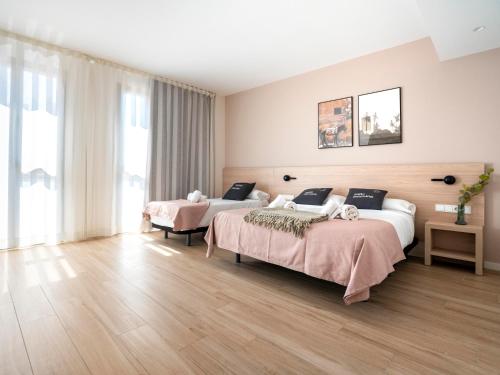 two beds in a hotel room with wooden floors at Limehome Barcelona Carrer de Besalú 82 in Barcelona