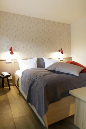 a bedroom with a bed with two lights on the wall at Hotel Aarnhoog in Keitum