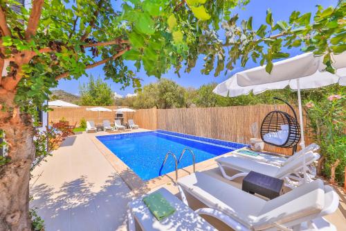 una piscina con sedie bianche e ombrellone e una piscina di Villa Grando 2 a Kaş