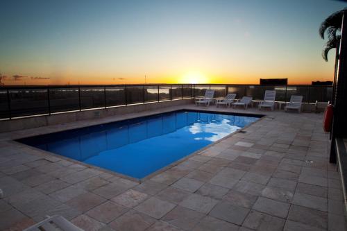 a swimming pool on the roof of a building with the sunset at Metropolitan Hotel Brasília in Brasilia