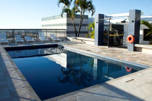 a swimming pool with chairs and a building at Metropolitan Hotel Brasília in Brasilia