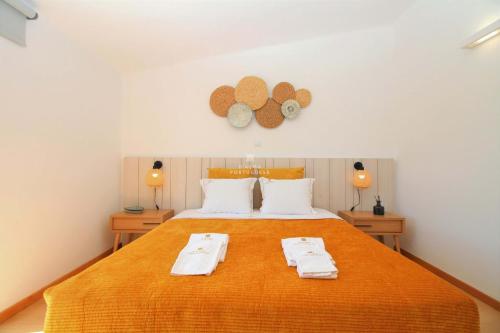 a bedroom with a large orange bed with two towels on it at Sao Rafael Beach Apartment - By Dalma Portuguesa in Albufeira