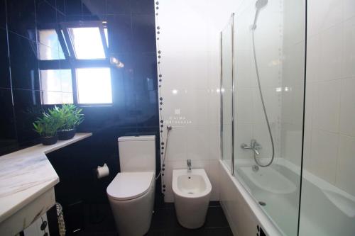 a bathroom with a toilet and a tub and a sink at Sao Rafael Beach Apartment - By Dalma Portuguesa in Albufeira