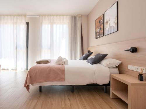 a bedroom with a large bed with white sheets and blue pillows at Limehome Barcelona Carrer de Besalú 82 in Barcelona