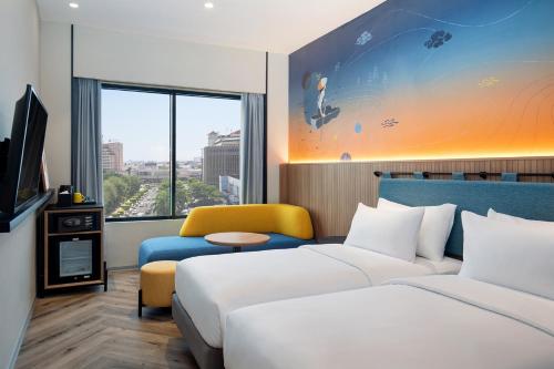 ibis Styles Semarang Simpang Lima في سيمارانغ: غرفة فندقية بسريرين واريكة