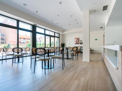 a meeting room with chairs and tables and windows at Limehome Barcelona Carrer de Besalú 82 in Barcelona