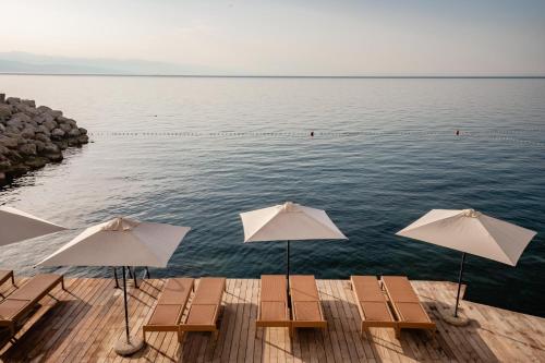 Hotel Istra - Liburnia في أوباتيا: رصيف به كراسي ومظلات على الماء