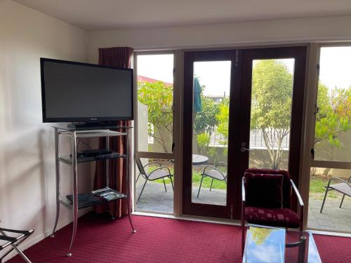 a living room with a flat screen tv and sliding glass doors at Chantillys Motor Lodge in Taupo