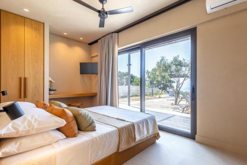 sypialnia z łóżkiem i dużym oknem w obiekcie Paloubi Estate w mieście Sinarádes