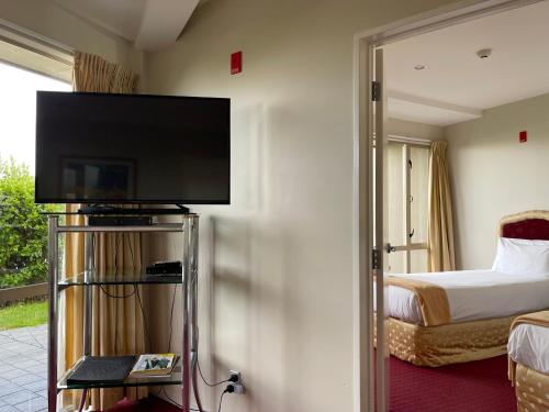 a hotel room with a bed and a flat screen tv at Chantillys Motor Lodge in Taupo