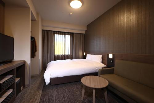 ein Hotelzimmer mit einem Bett und einem Sofa in der Unterkunft Dormy Inn Okayama Natural Hot Spring in Okayama