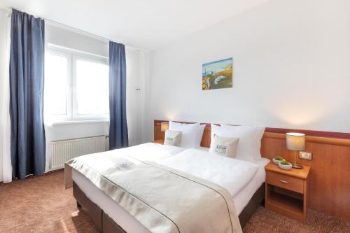 a bedroom with a large white bed with blue curtains at Novum Hotel Aldea Berlin Centrum in Berlin